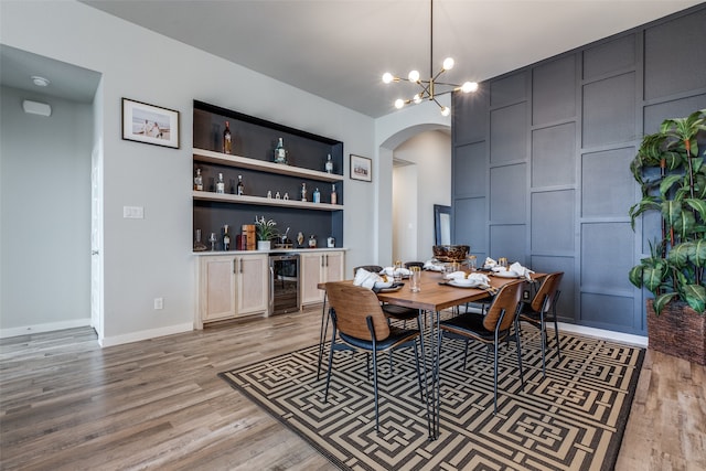 dining area featuring light hardwood / wood-style floors, built in shelves, bar area, and wine cooler