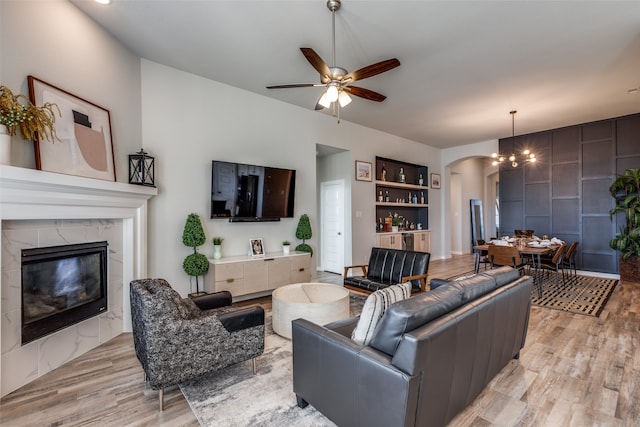 living room with built in shelves, light hardwood / wood-style floors, a fireplace, and ceiling fan