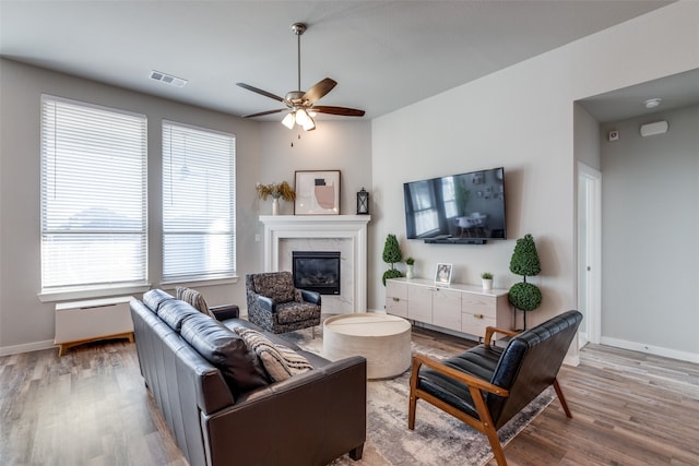 living room featuring hardwood / wood-style flooring, ceiling fan, and a fireplace