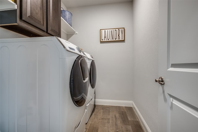 laundry room featuring washing machine and dryer, cabinets, and wood-type flooring