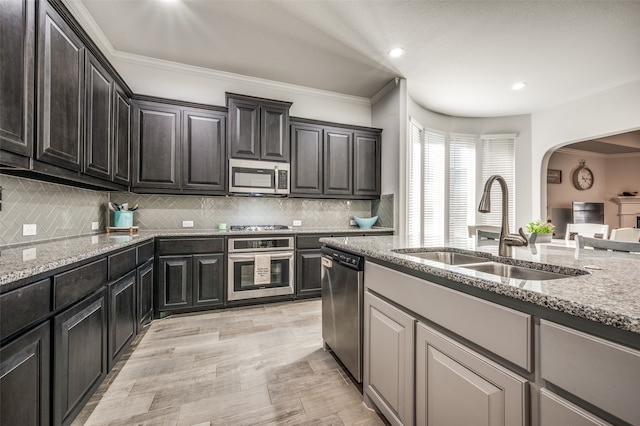 kitchen with tasteful backsplash, light stone counters, sink, and stainless steel appliances