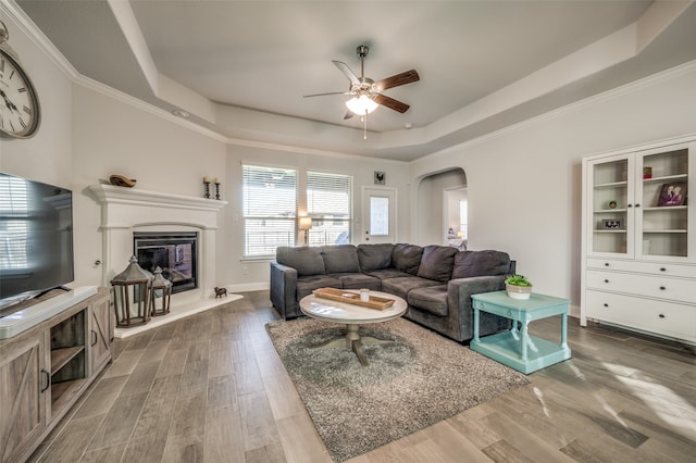 living room with a tray ceiling, ceiling fan, hardwood / wood-style floors, and ornamental molding