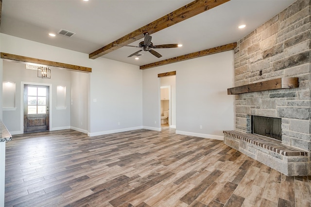 unfurnished living room featuring a stone fireplace, hardwood / wood-style floors, and beamed ceiling