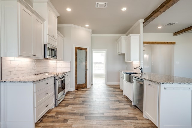 kitchen featuring white cabinetry, sink, light stone counters, appliances with stainless steel finishes, and light wood-type flooring