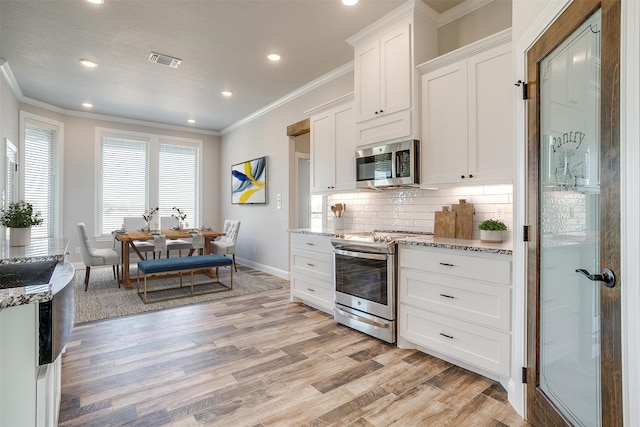 kitchen featuring white cabinetry, stainless steel appliances, light stone counters, light hardwood / wood-style flooring, and crown molding