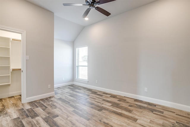 unfurnished bedroom featuring vaulted ceiling, ceiling fan, a spacious closet, light hardwood / wood-style floors, and a closet