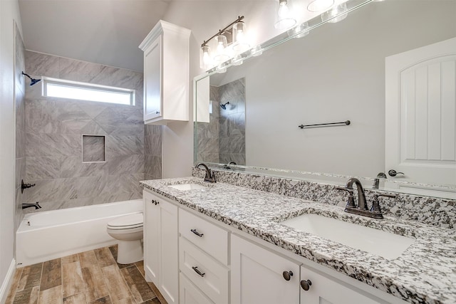 full bathroom featuring vanity, hardwood / wood-style floors, tiled shower / bath combo, and toilet