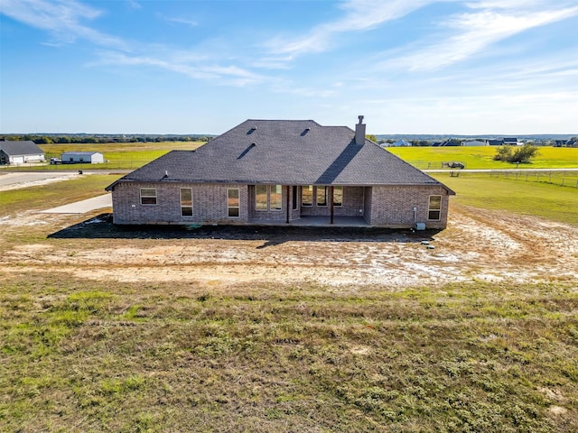 back of house featuring a yard, a rural view, and a patio