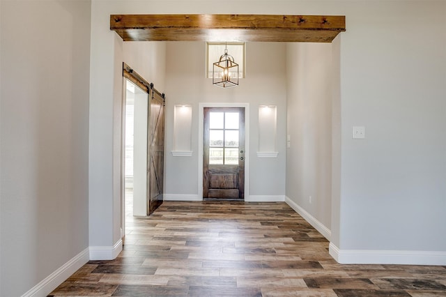 foyer featuring a barn door, dark hardwood / wood-style flooring, and beamed ceiling