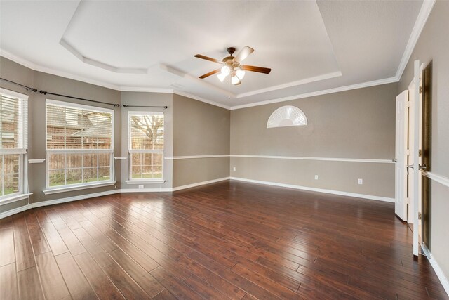 unfurnished room featuring dark wood-type flooring, a raised ceiling, ceiling fan, and crown molding