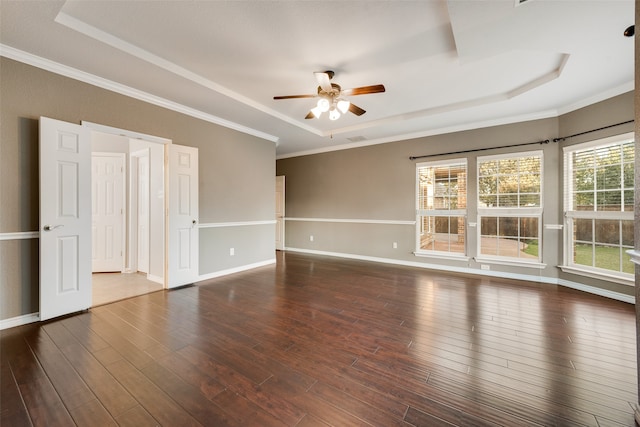 empty room featuring ceiling fan, a tray ceiling, dark hardwood / wood-style floors, and crown molding