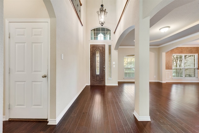 entryway featuring dark wood-type flooring, crown molding, and plenty of natural light