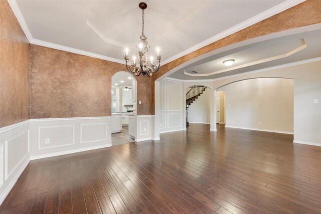 spare room featuring dark wood-type flooring, a chandelier, and ornamental molding