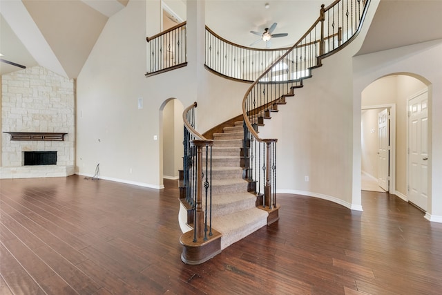 interior space with dark wood-type flooring, a stone fireplace, and high vaulted ceiling