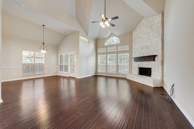 unfurnished living room with dark hardwood / wood-style flooring, high vaulted ceiling, a stone fireplace, and ceiling fan