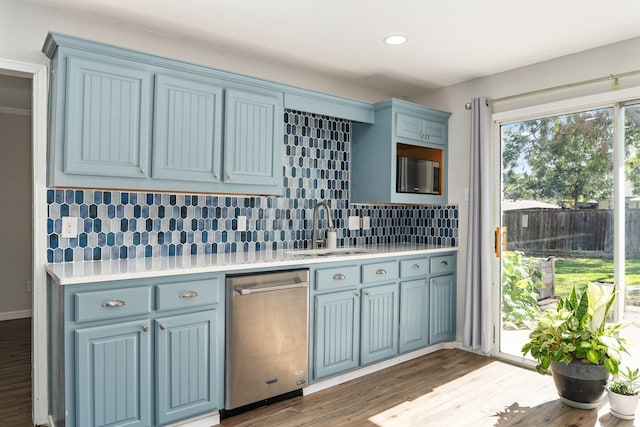 kitchen with blue cabinetry, sink, light hardwood / wood-style floors, decorative backsplash, and appliances with stainless steel finishes