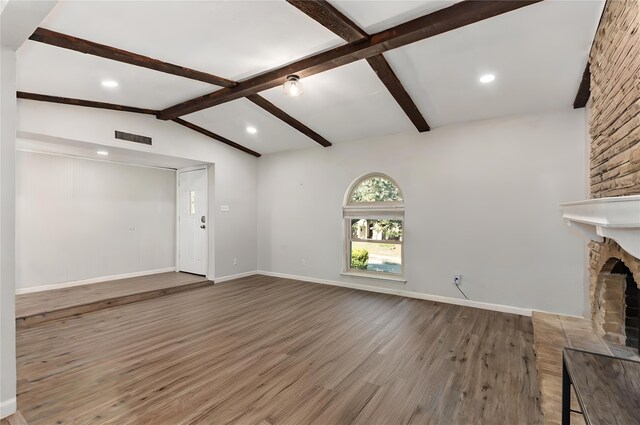 living room with lofted ceiling with beams, a fireplace, and light hardwood / wood-style floors