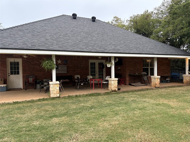 back of property with a patio, a lawn, and french doors