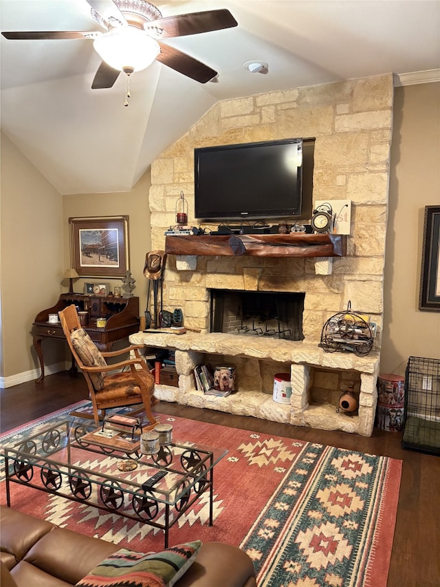 living room featuring dark hardwood / wood-style flooring, vaulted ceiling, ornamental molding, ceiling fan, and a fireplace