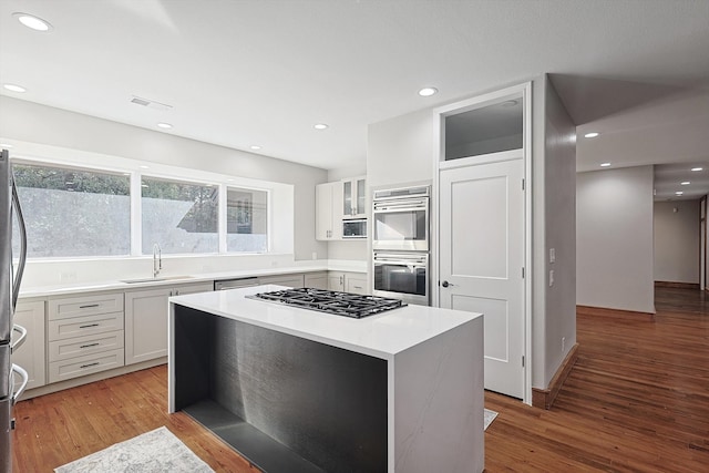 kitchen featuring stainless steel appliances, white cabinets, sink, and a kitchen island