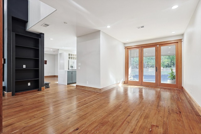 unfurnished living room with light hardwood / wood-style flooring and french doors