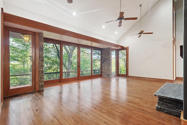 unfurnished living room with high vaulted ceiling, a wealth of natural light, ceiling fan, and light hardwood / wood-style flooring