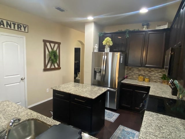 kitchen with sink, tasteful backsplash, dark hardwood / wood-style floors, stainless steel refrigerator with ice dispenser, and a kitchen island