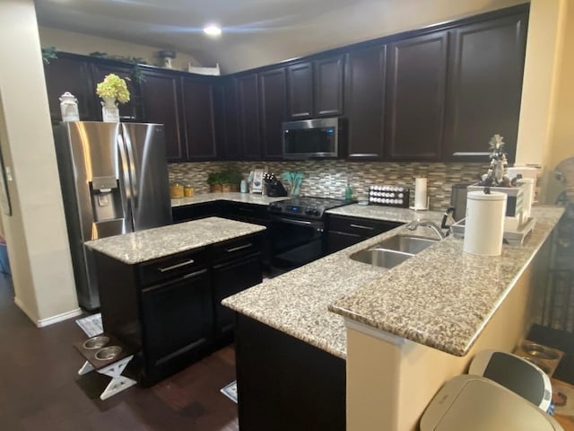 2748 Morning Song Dr, Little Elm, TX 75068 - kitchen with stainless steel appliances, a sink, a peninsula, light stone counters, and decorative backsplash