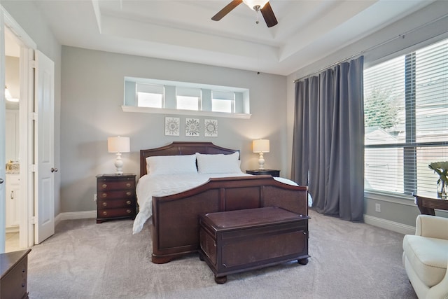 carpeted bedroom featuring ceiling fan, multiple windows, and a raised ceiling