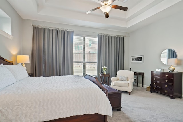 carpeted bedroom featuring ceiling fan and a tray ceiling