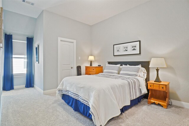 bedroom featuring light colored carpet and lofted ceiling