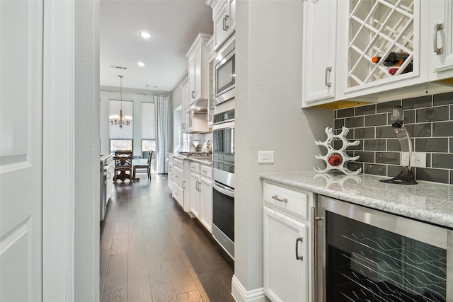 kitchen featuring white cabinets, decorative backsplash, light stone counters, and beverage cooler