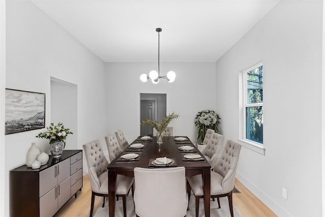 dining room with light wood-type flooring, an inviting chandelier, and baseboards