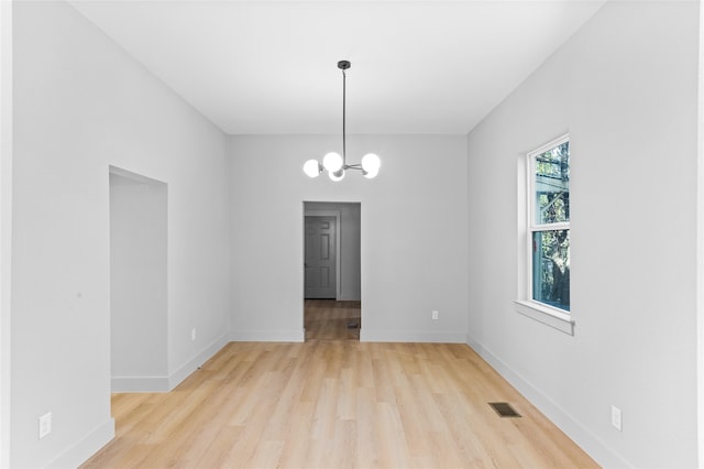 unfurnished dining area featuring a chandelier, light wood-type flooring, visible vents, and baseboards