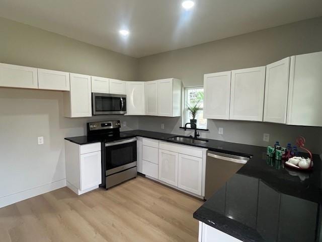 kitchen featuring stainless steel appliances, light wood finished floors, a sink, and white cabinets