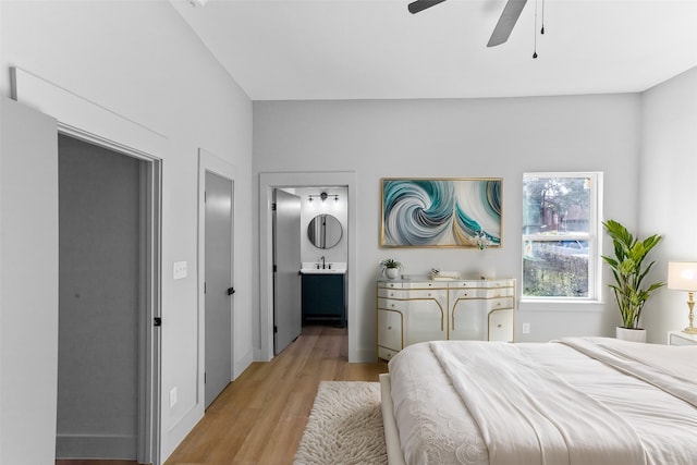 bedroom with light wood finished floors, connected bathroom, a ceiling fan, and a sink