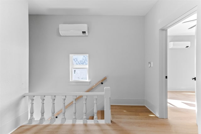 stairs featuring baseboards, wood finished floors, and a wall mounted air conditioner