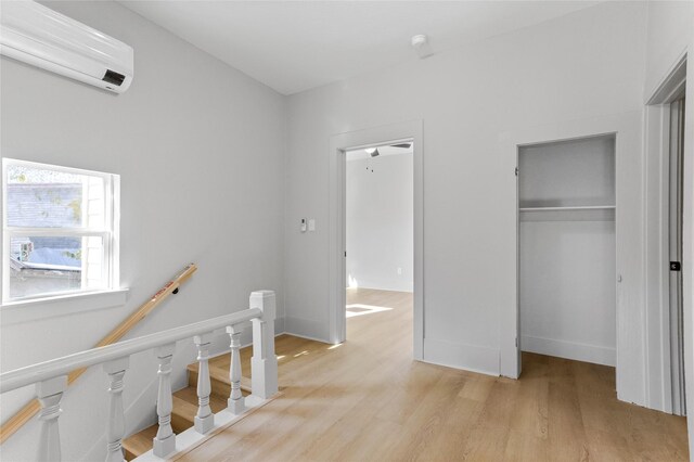 interior space featuring a wall unit AC, light wood-style flooring, baseboards, and a closet