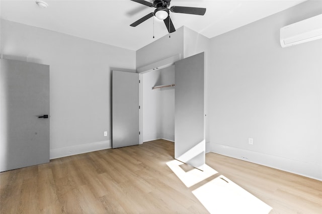 unfurnished bedroom featuring baseboards, ceiling fan, wood finished floors, a closet, and a wall mounted AC