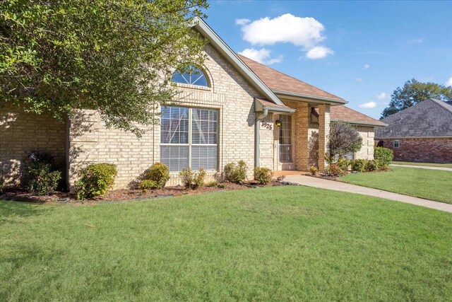 view of front of home featuring brick siding and a front lawn