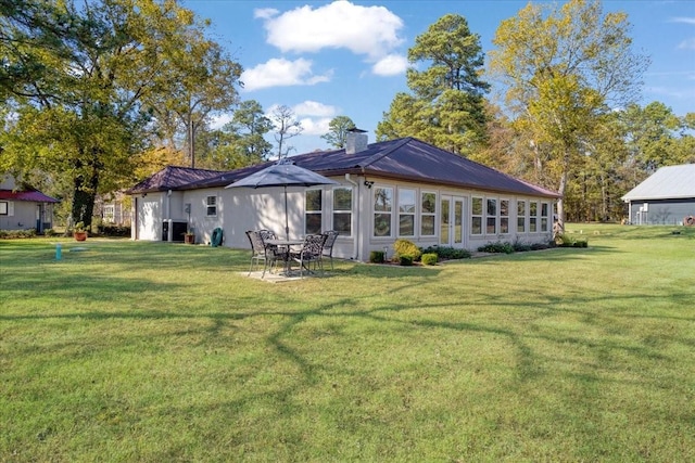 rear view of house with a chimney, a yard, and metal roof