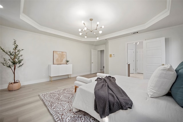 bedroom with light hardwood / wood-style flooring, an inviting chandelier, crown molding, and a tray ceiling