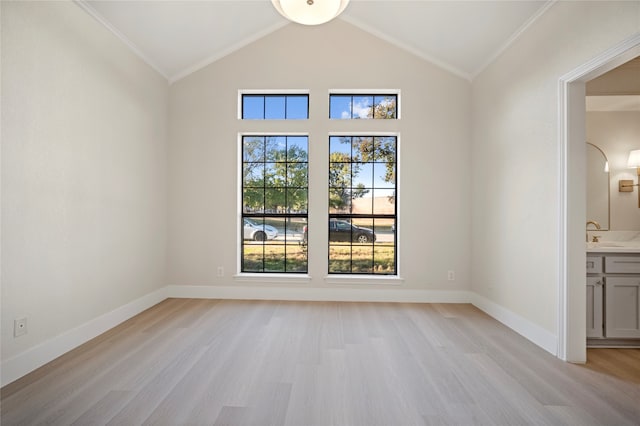 empty room featuring lofted ceiling, light hardwood / wood-style floors, and ornamental molding