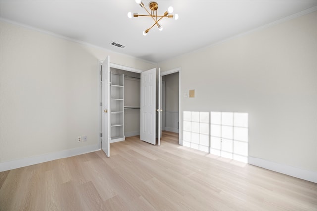 unfurnished bedroom featuring a chandelier, light hardwood / wood-style floors, a closet, and crown molding