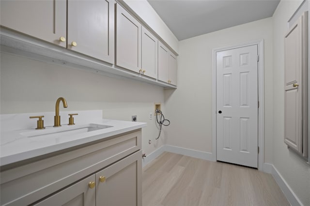 laundry room with electric dryer hookup, cabinets, sink, light hardwood / wood-style flooring, and washer hookup