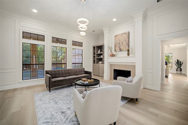 living room with light hardwood / wood-style floors, built in features, and ornamental molding