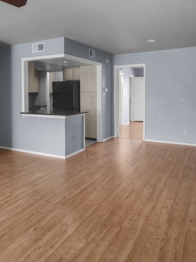 unfurnished living room featuring ceiling fan and light hardwood / wood-style flooring