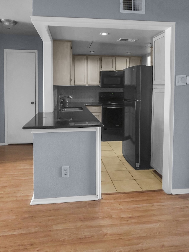 kitchen with kitchen peninsula, sink, black appliances, and light wood-type flooring