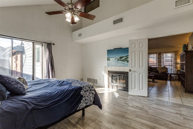 bedroom with ceiling fan, multiple windows, light hardwood / wood-style flooring, and high vaulted ceiling