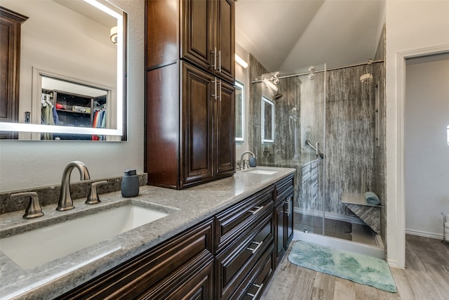 bathroom with hardwood / wood-style flooring, vanity, a tile shower, and vaulted ceiling